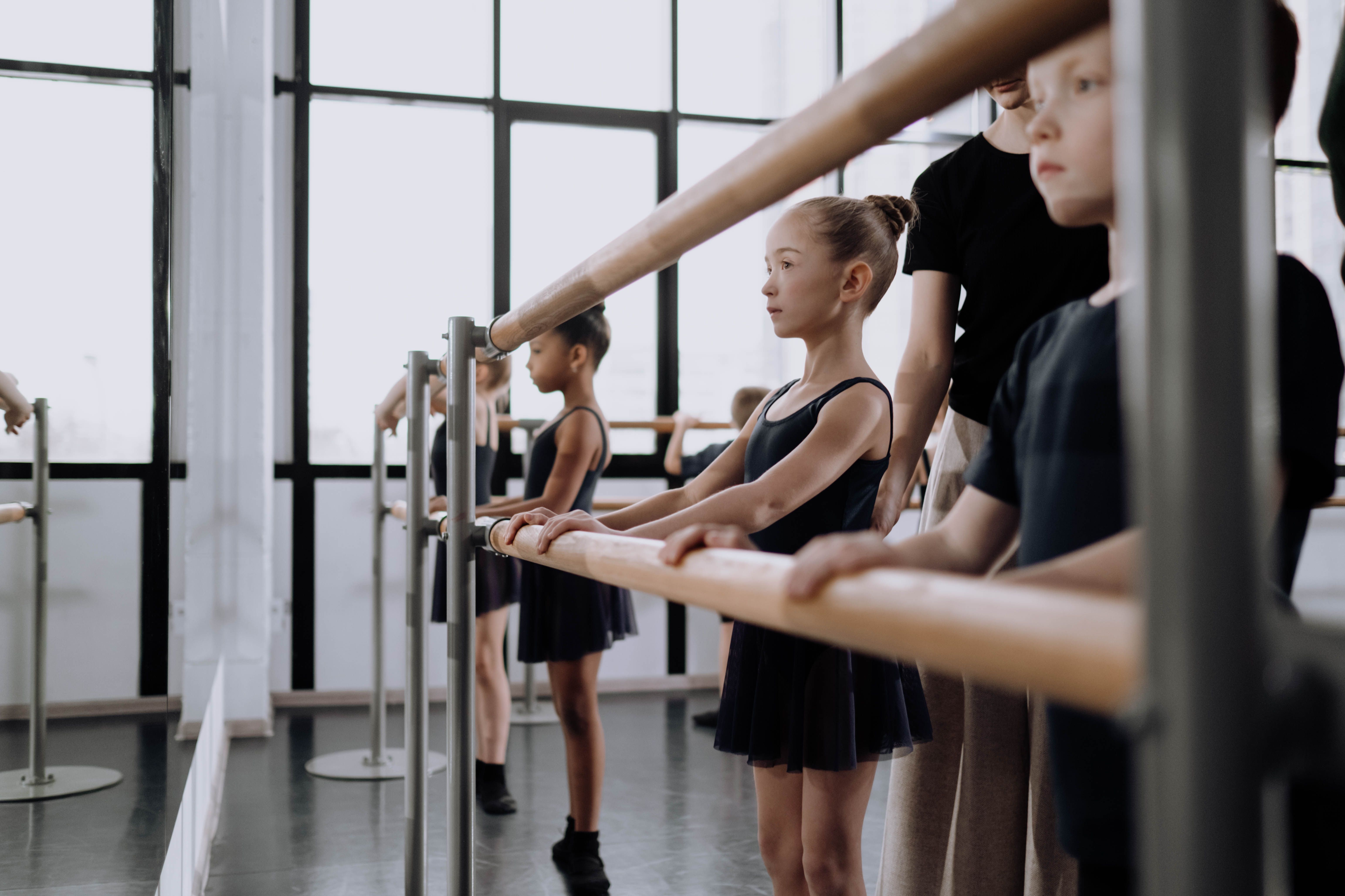 Young ballet students practicing at the barre in a bright studio